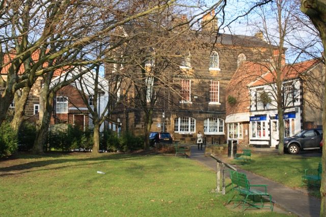 Bakehouse Square in Guisborough with older brick buildings beside a small green